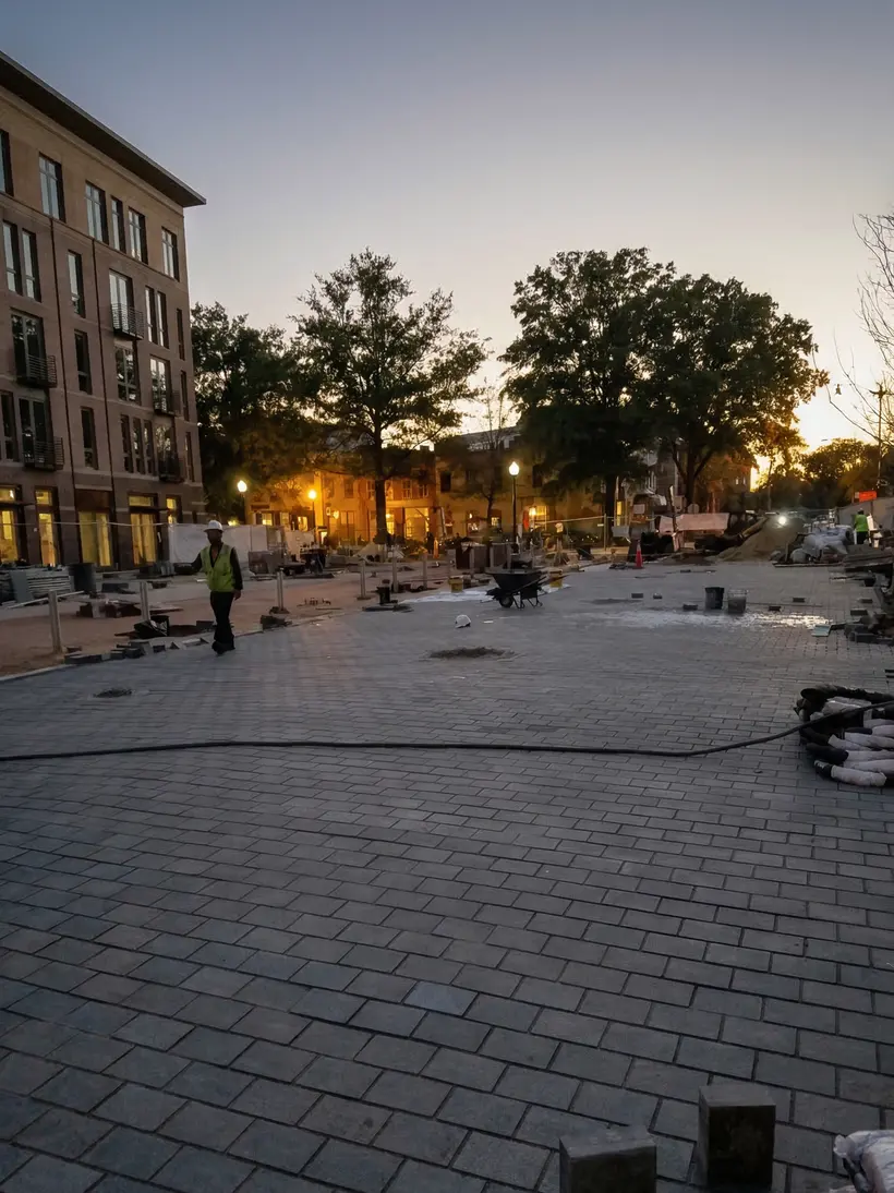 Plaza at dusk with string lights and young trees