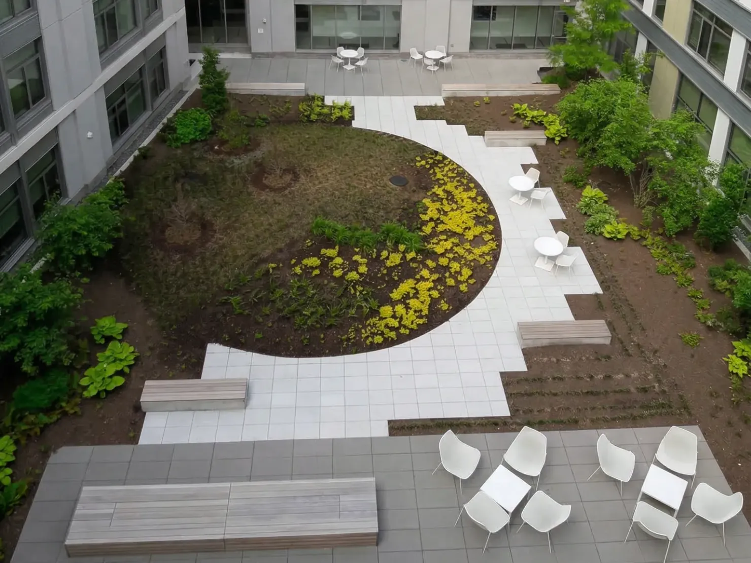 Finished courtyard garden seen from above: circular lawn, paver plaza and planted beds kept immaculate